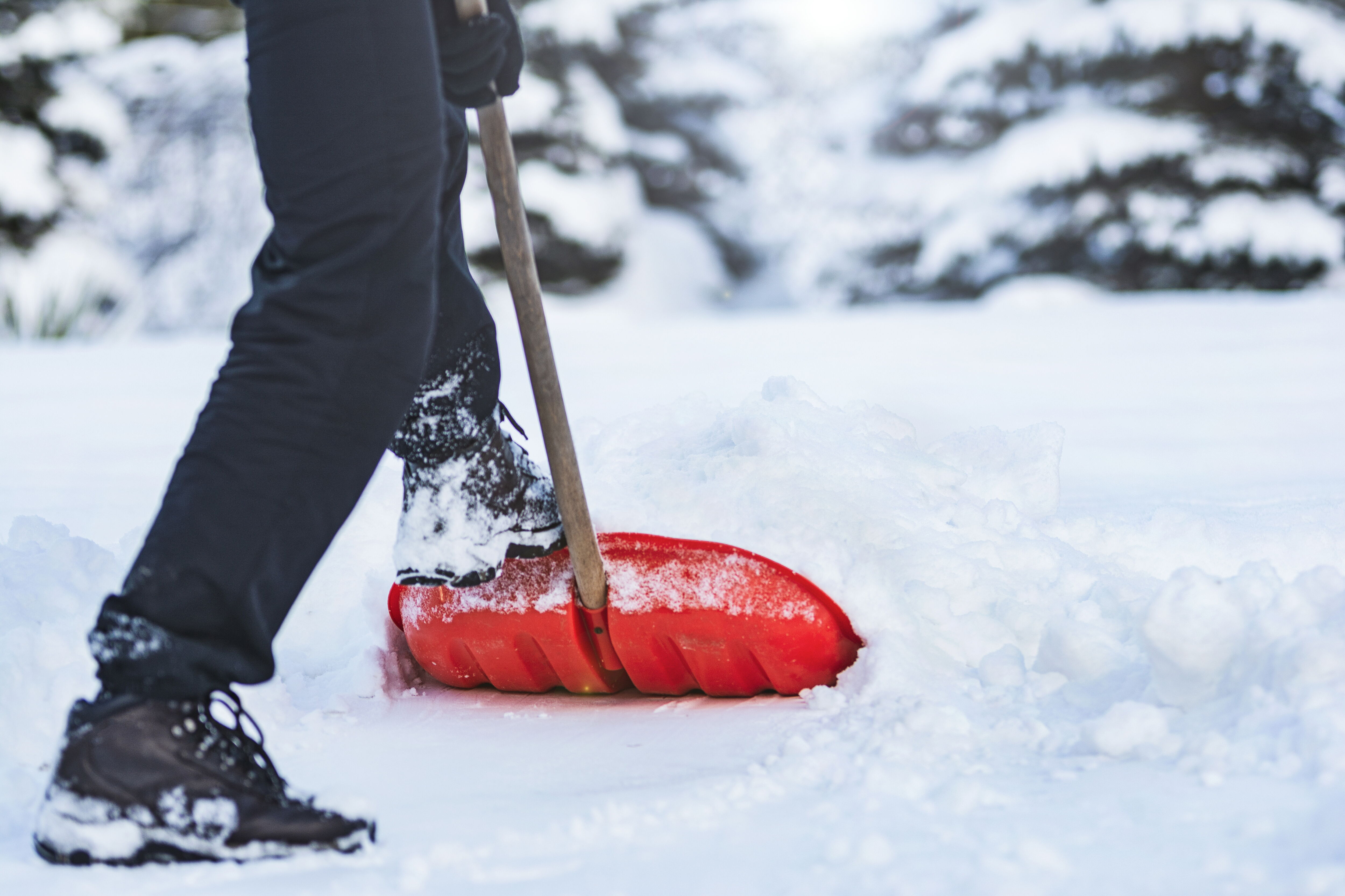 Auf dem Moodbild ist eine Person abgebildet, die mit einer Schneeschaufel eine Fläche von Schnee befreit.